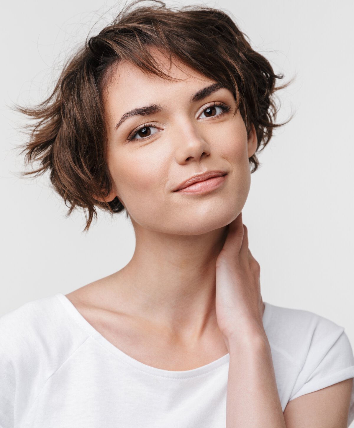 Woman with brown hair touching her neck